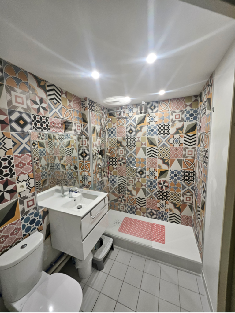 Cette image représente une rénovation de salle de bain, remplacement d'une baignoire par un bac a douche+ carrelages multicolores a motif géométriques